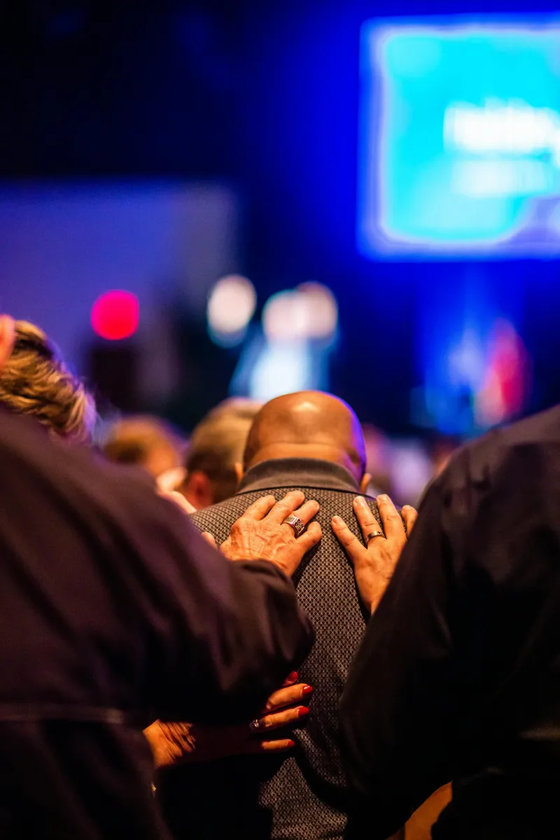 A diverse congregation in prayer, the Saints stepping out of the pews